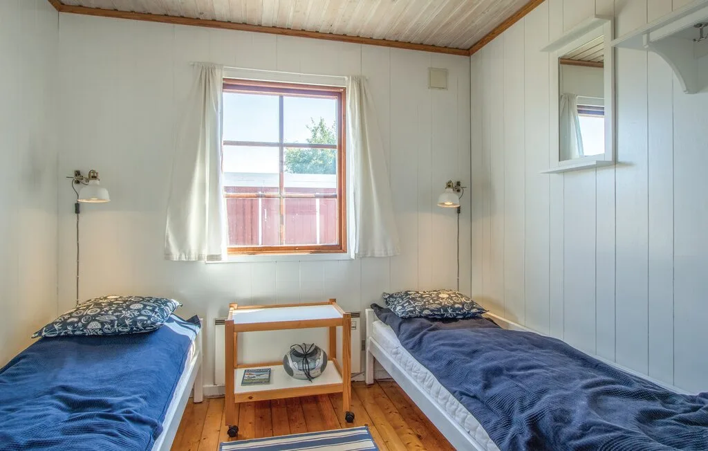 Un dormitorio luminoso con dos camas, una ventana y una mesita.