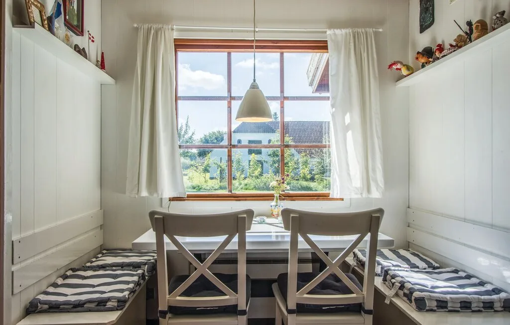 Un rincón comedor luminoso con una mesa, sillas y una ventana grande.