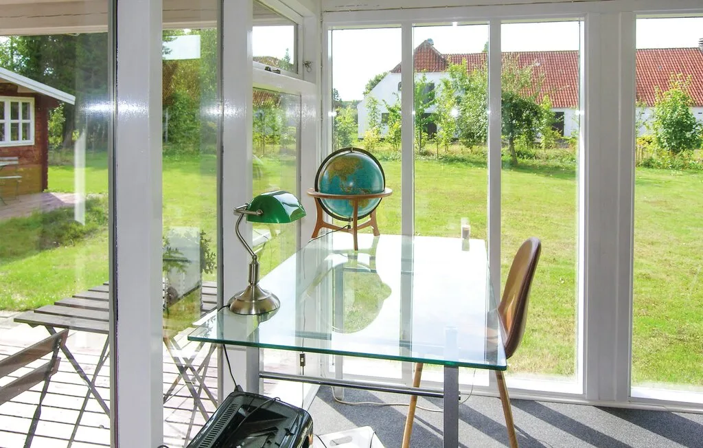 Un luminoso solárium con un escritorio de cristal y un globo junto a grandes ventanas.