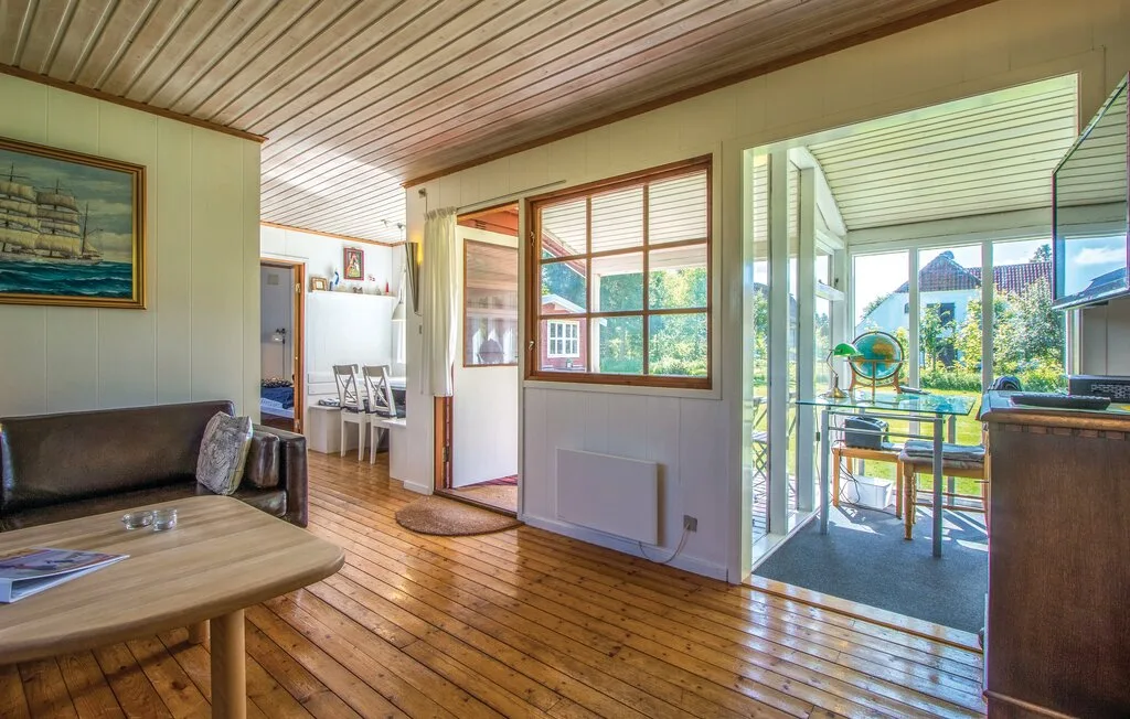 Una sala de estar con suelo de madera y un comedor visible a través de la puerta abierta.