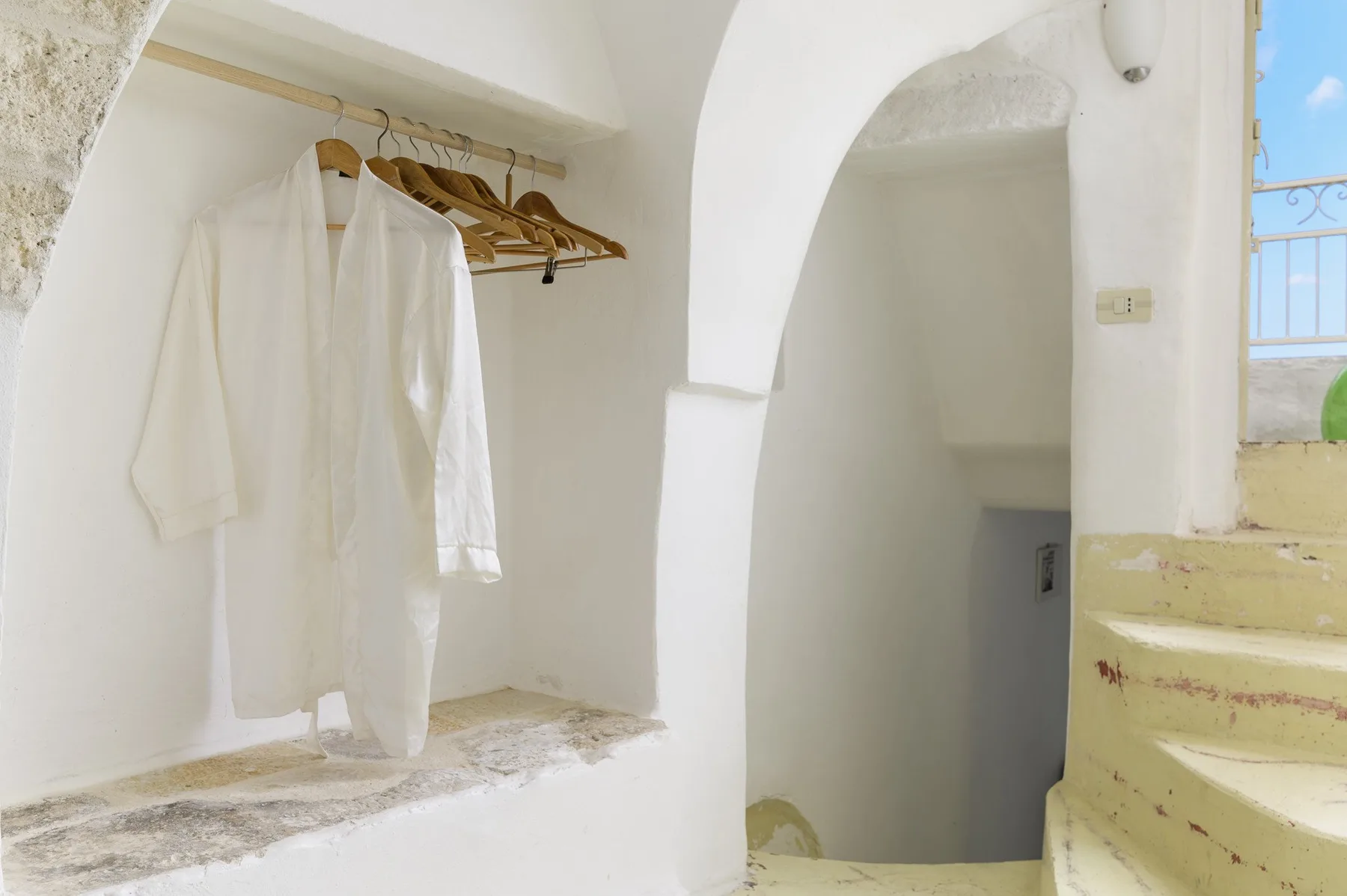 Una escalera interior blanca con batas colgadas junto a los escalones.