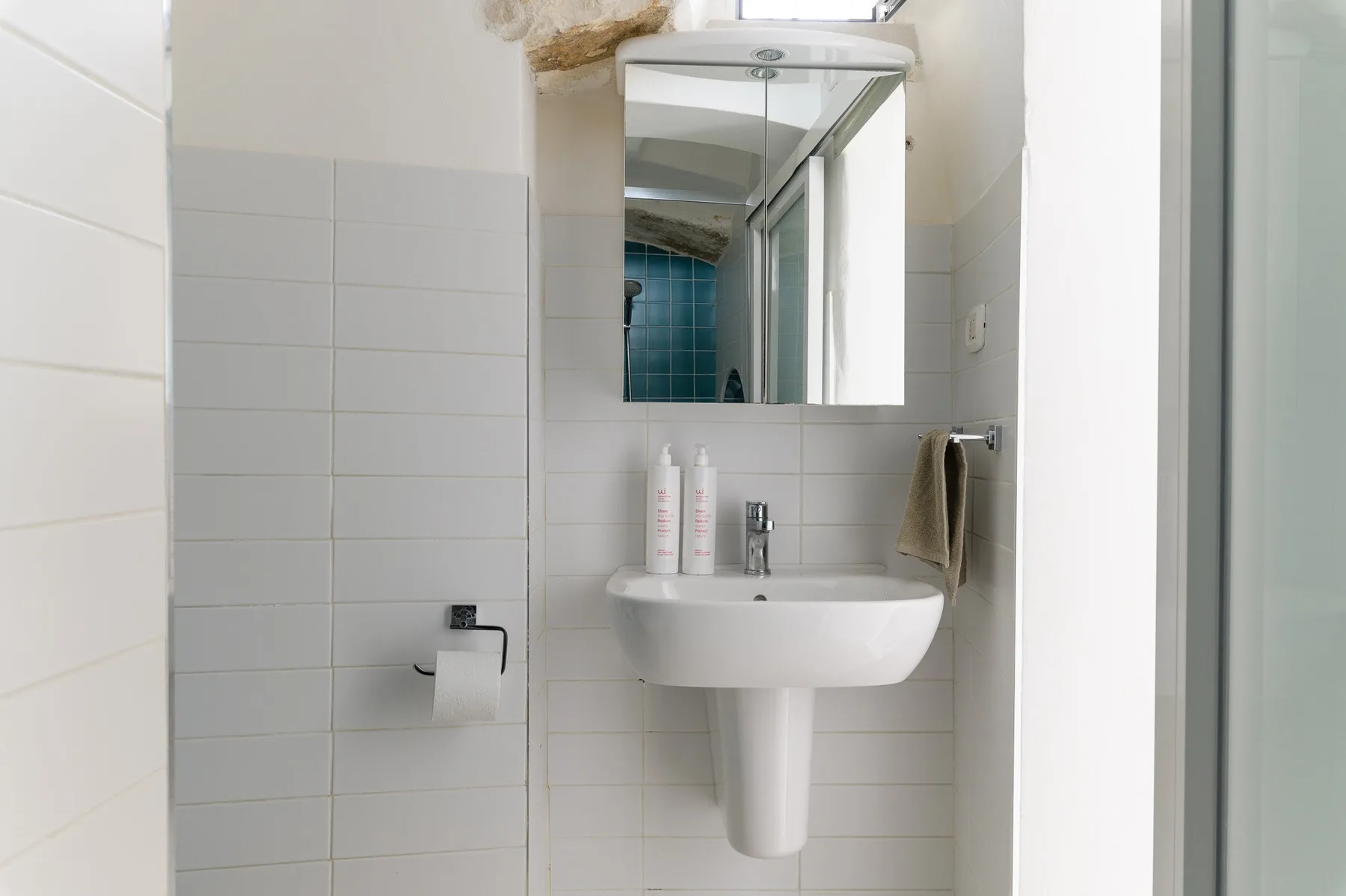 Un baño con azulejos, lavabo y espejo.
