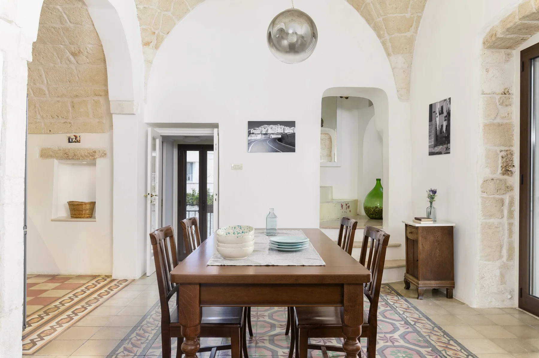 Un comedor con una mesa de madera y sillas bajo un techo abovedado.