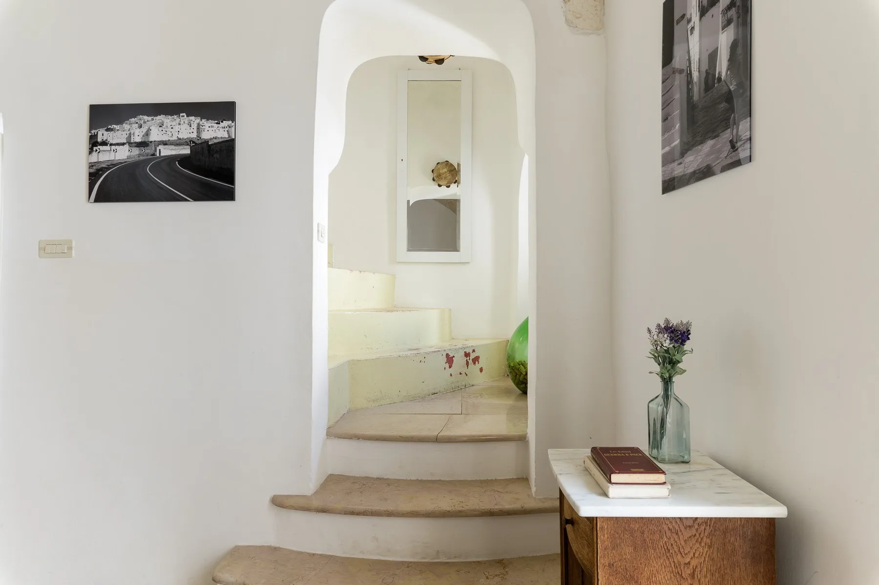 Un arco blanco da paso a una zona elevada para sentarse, con cuadros en las paredes.