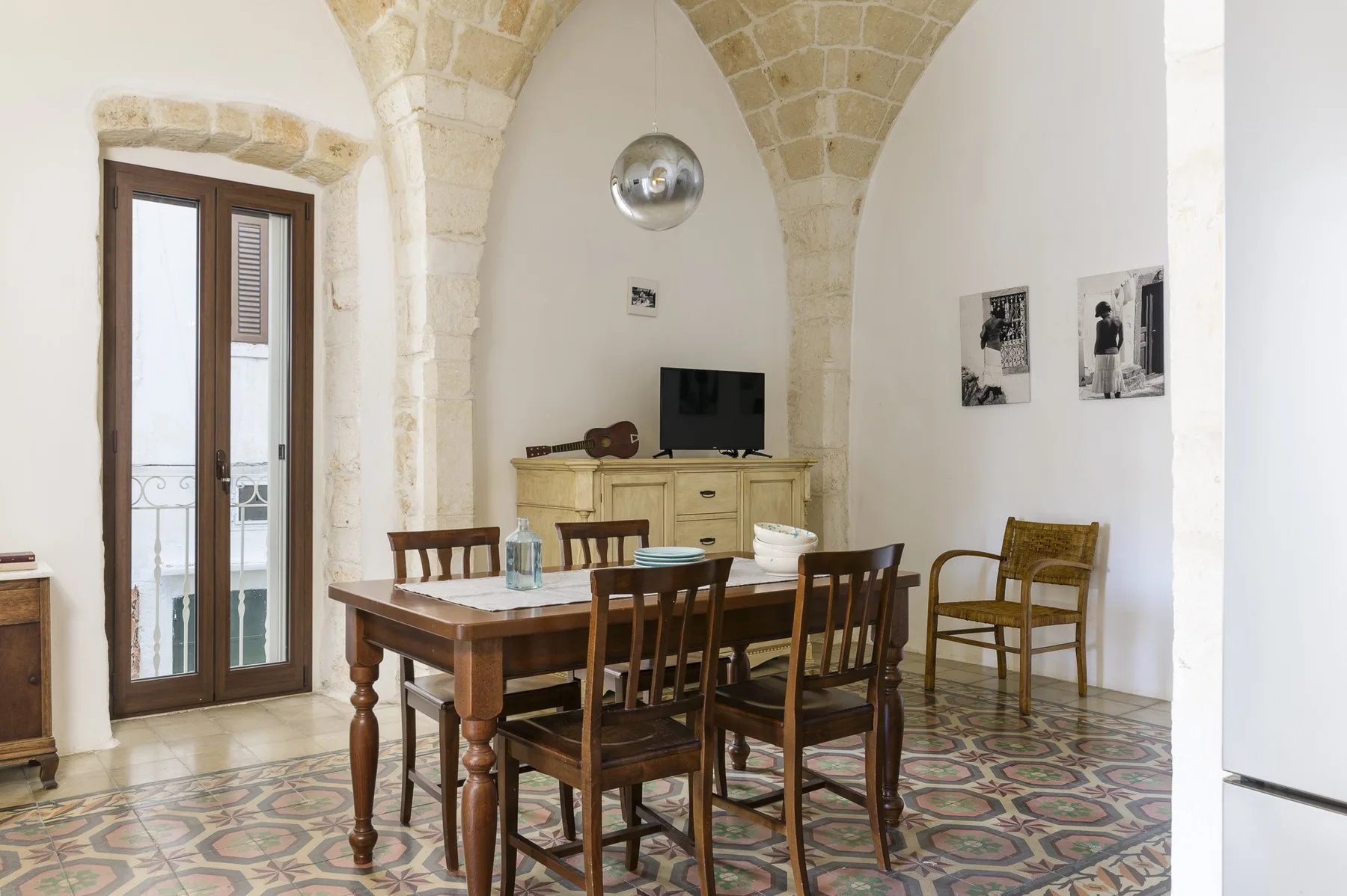 Un comedor con una mesa de madera y sillas bajo arcos de piedra.