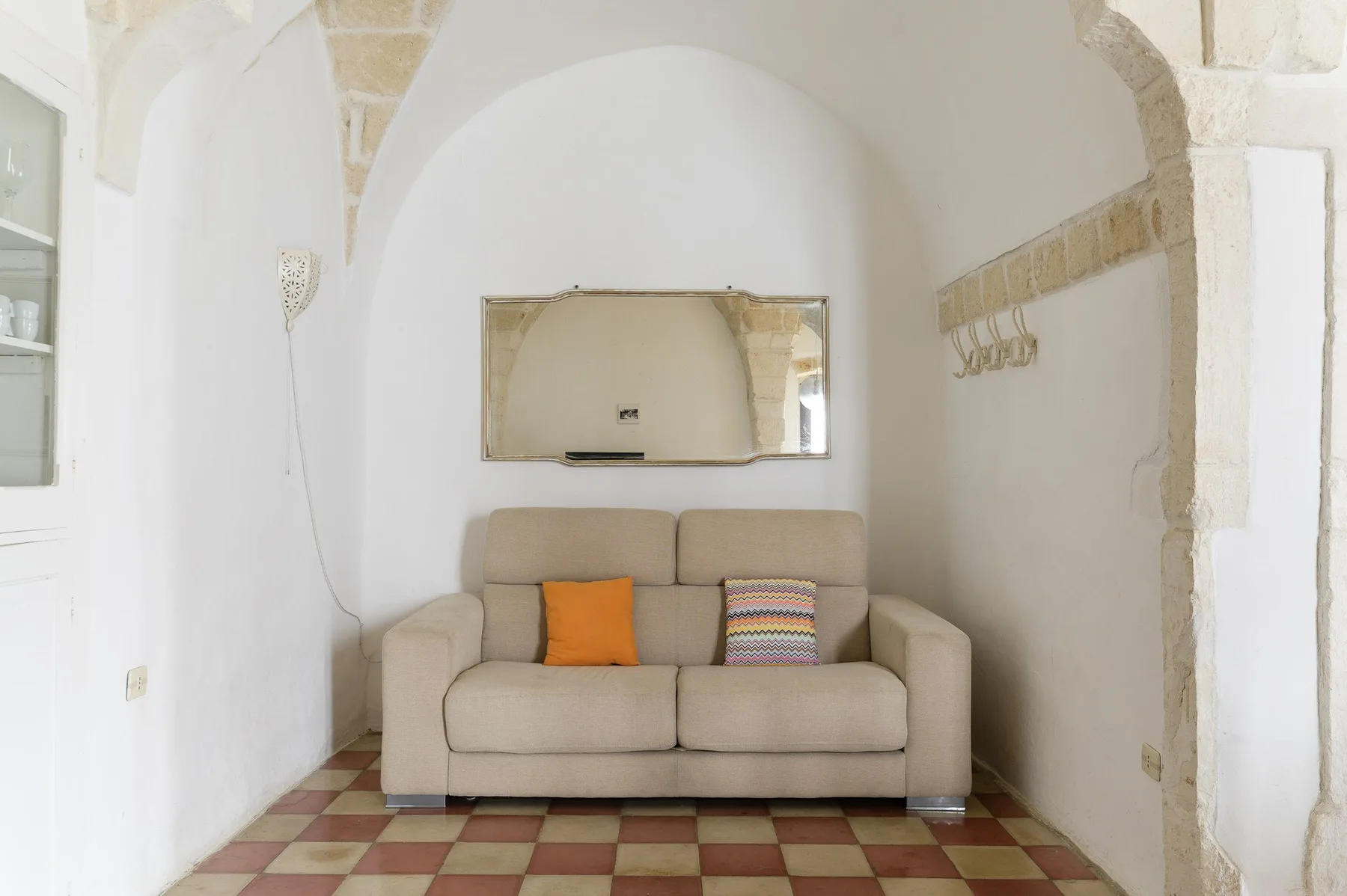 Una pequeña zona de estar con un sofá beige bajo un techo abovedado.