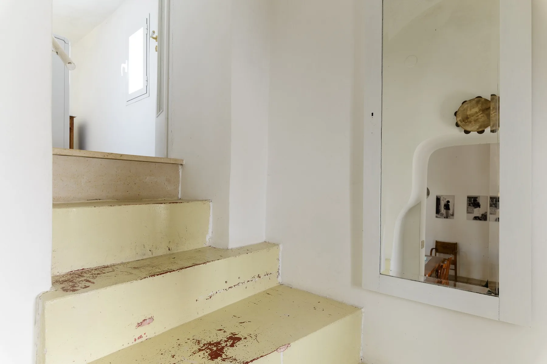 Una escalera con peldaños desgastados y un espejo en la pared.