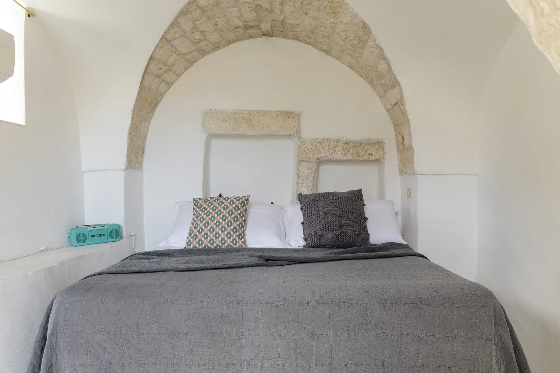 Un dormitorio con una cama bajo un arco de piedra.