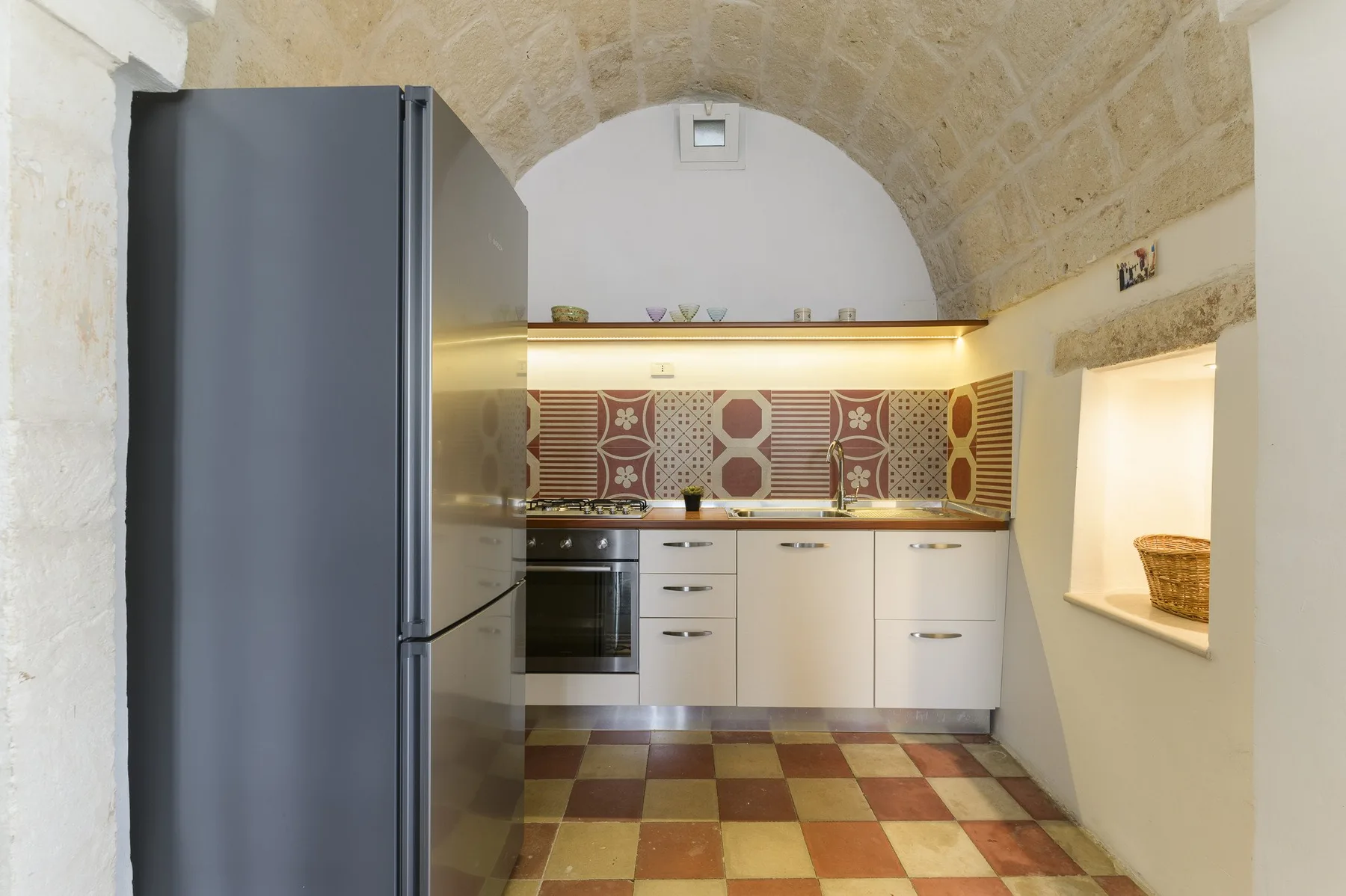Una cocina compacta con armarios blancos y un salpicadero estampado.