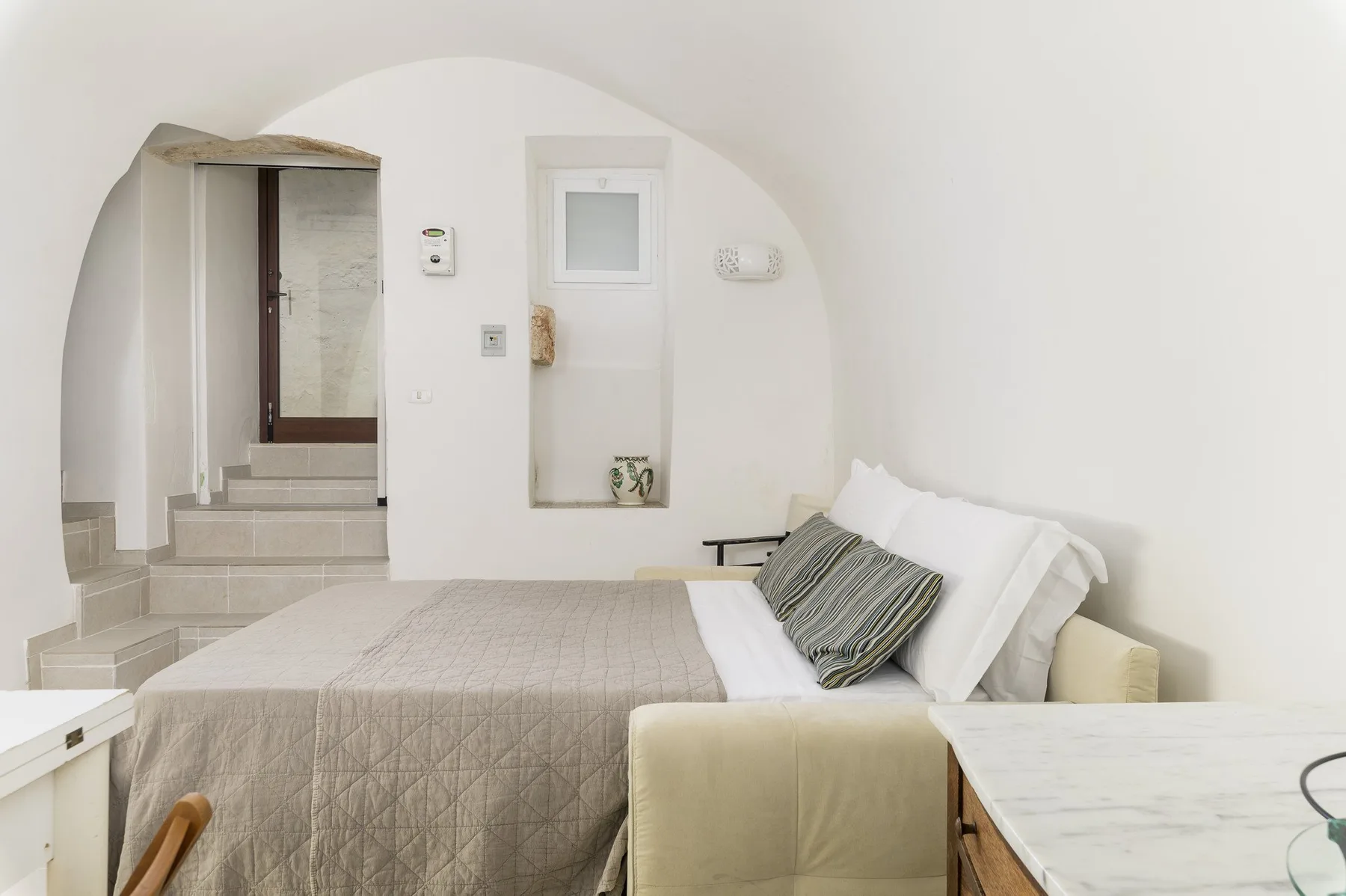 Un dormitorio con una cama bien tendida y una puerta en arco.