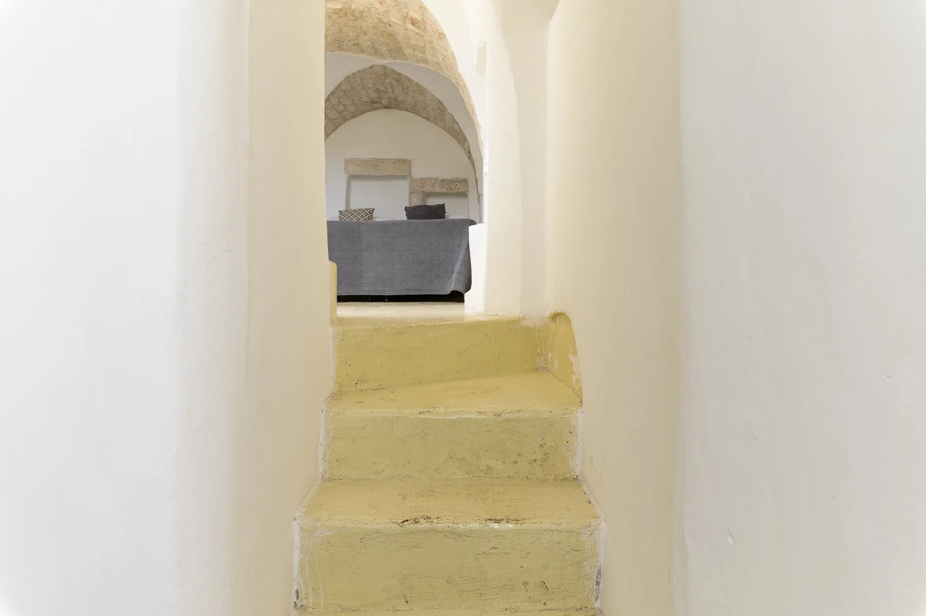 Una estrecha escalera interior conduce por un pasaje arqueado hacia una zona de estar.