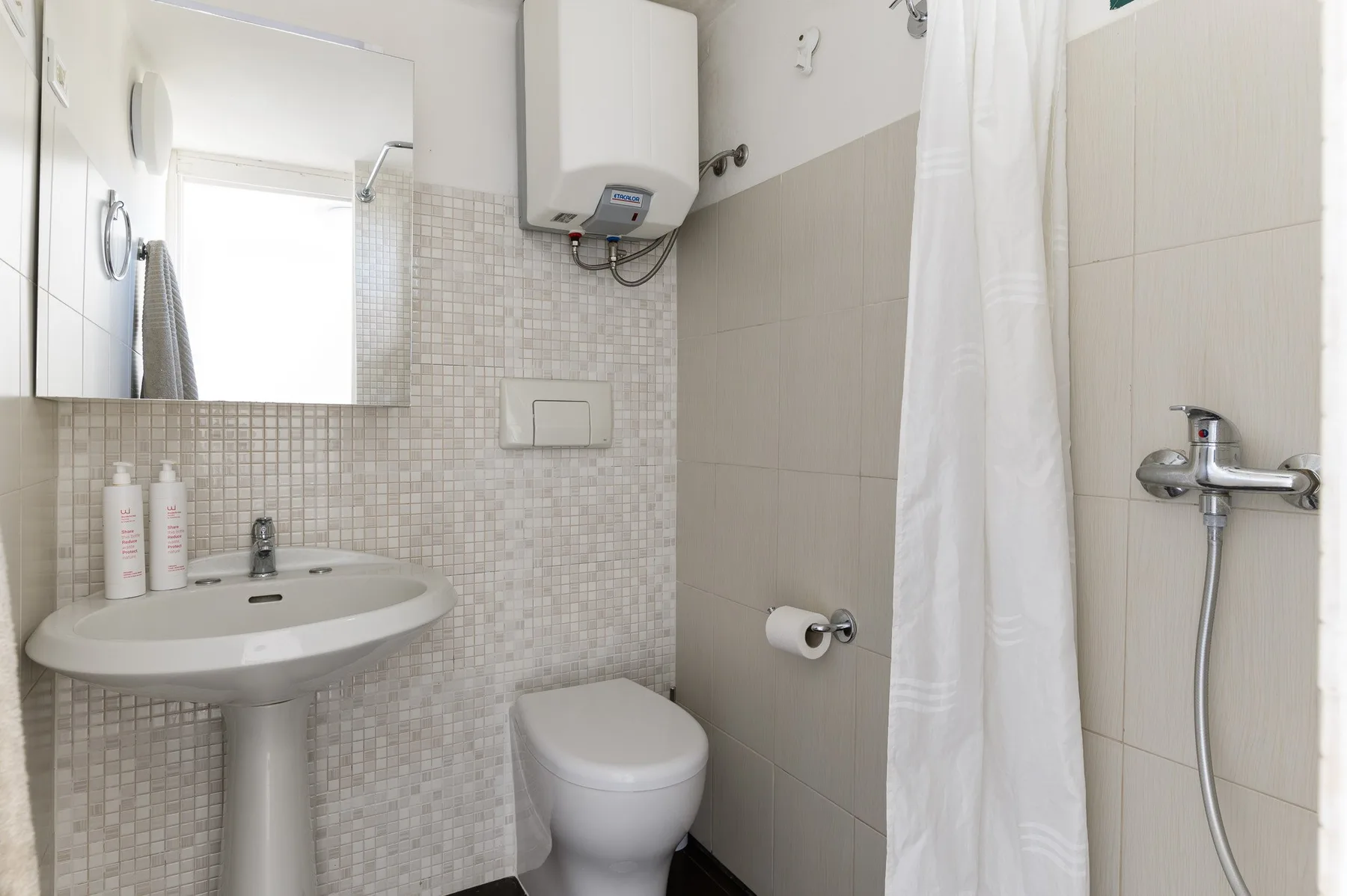 Un baño compacto con lavabo, inodoro y ducha con cortina.