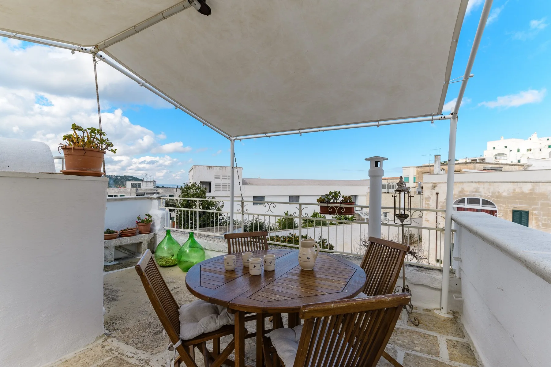 Una terraza en la azotea con una mesa redonda de madera bajo un toldo.