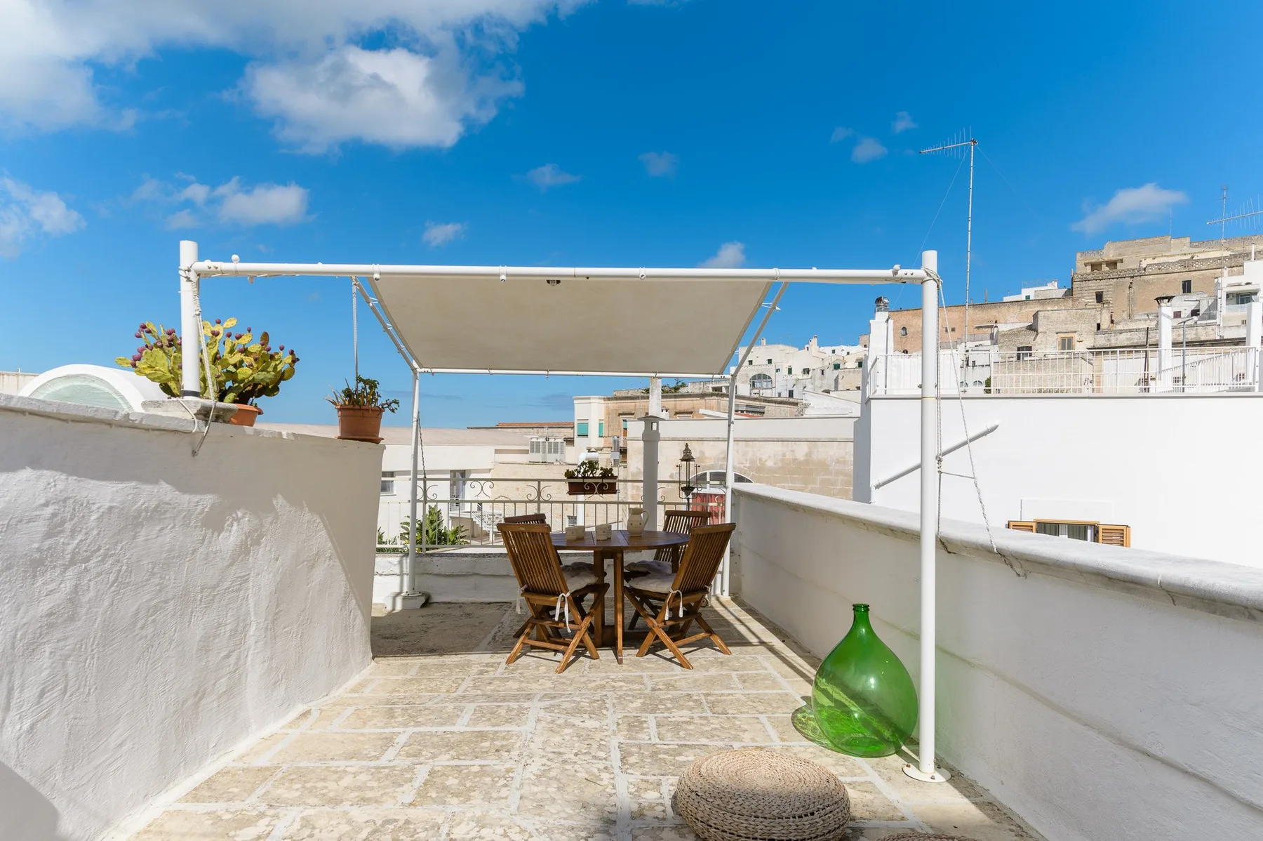 Una terraza en la azotea con una mesa de comedor y sillas a la sombra.