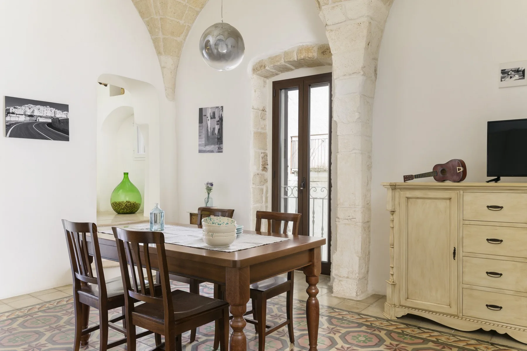 Comedor con una mesa y sillas de madera bajo un arco de piedra.