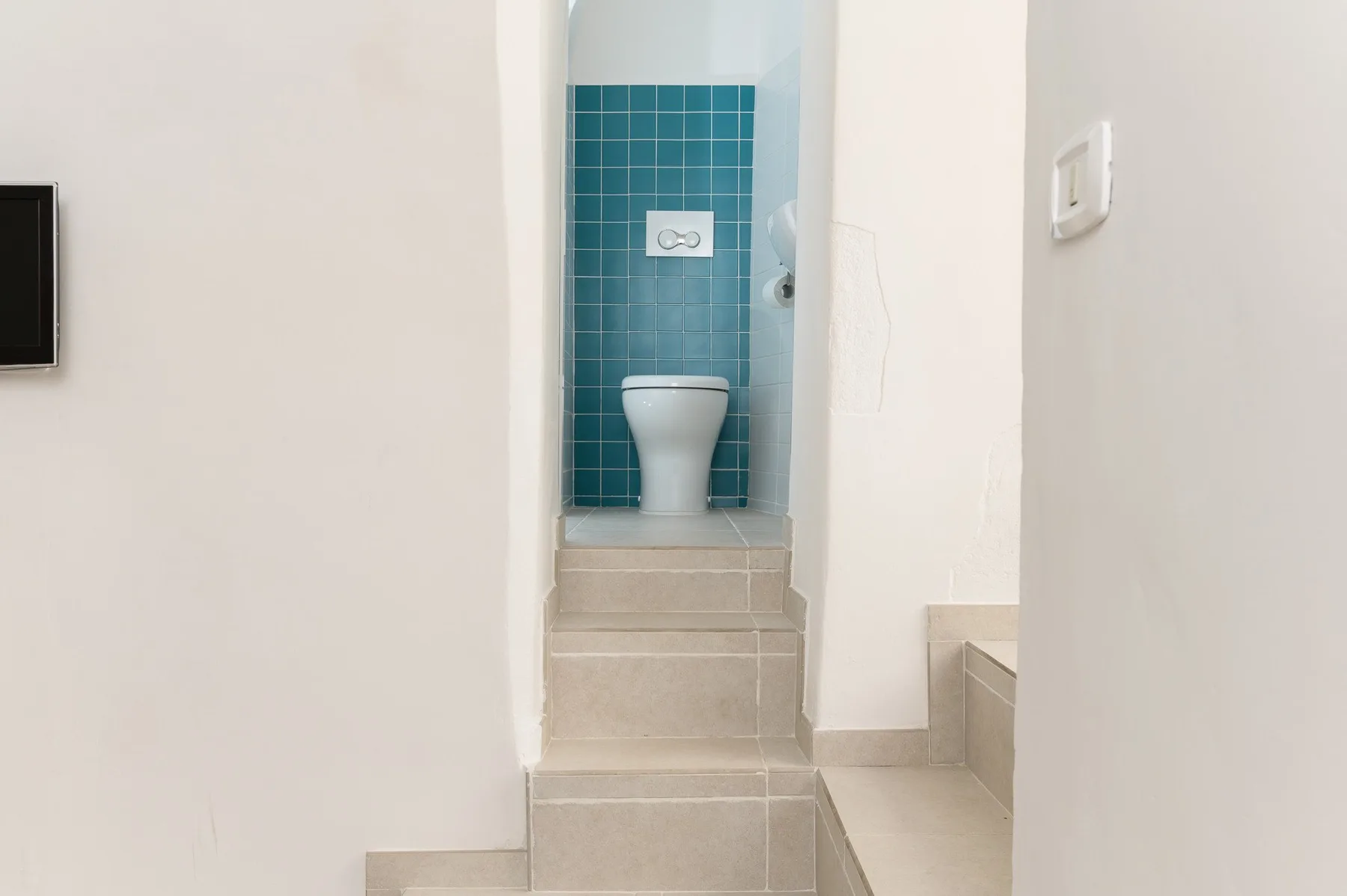 Se ve una zona de baño alicatada con un inodoro, más allá de unos escalones.