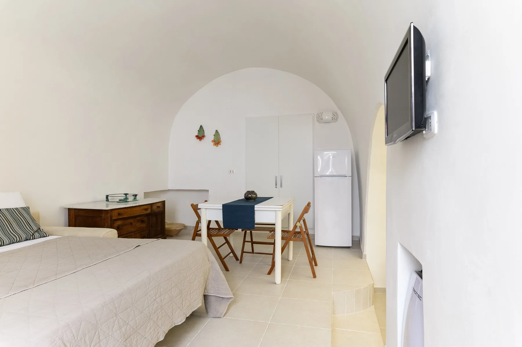 Un dormitorio con una cama, una mesa de comedor y un televisor.
