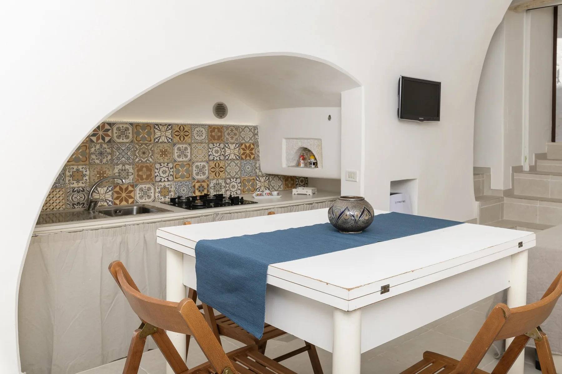 Una luminosa cocina-comedor con azulejos estampados detrás de la encimera y una mesa preparada.