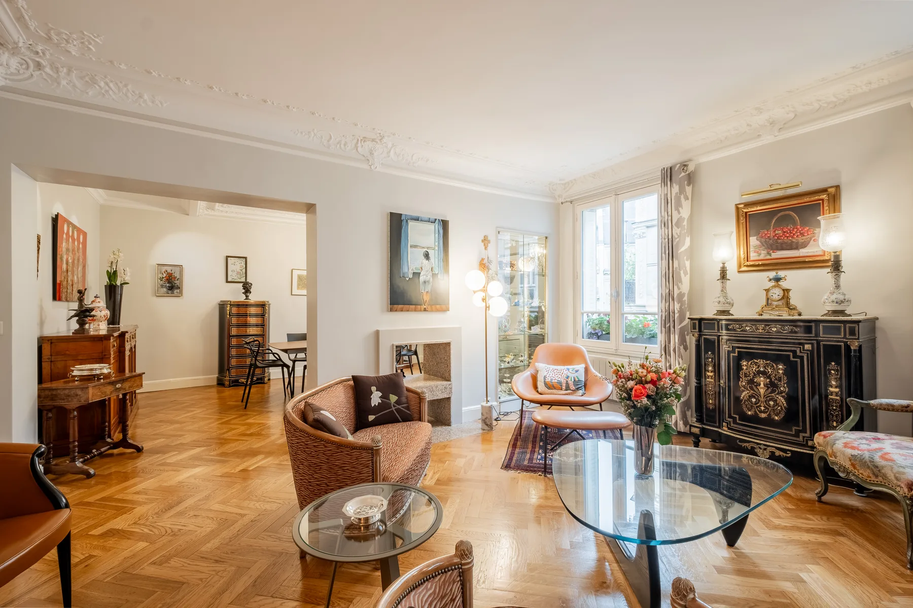 A bright living room with a glass coffee table and ornate fireplace.