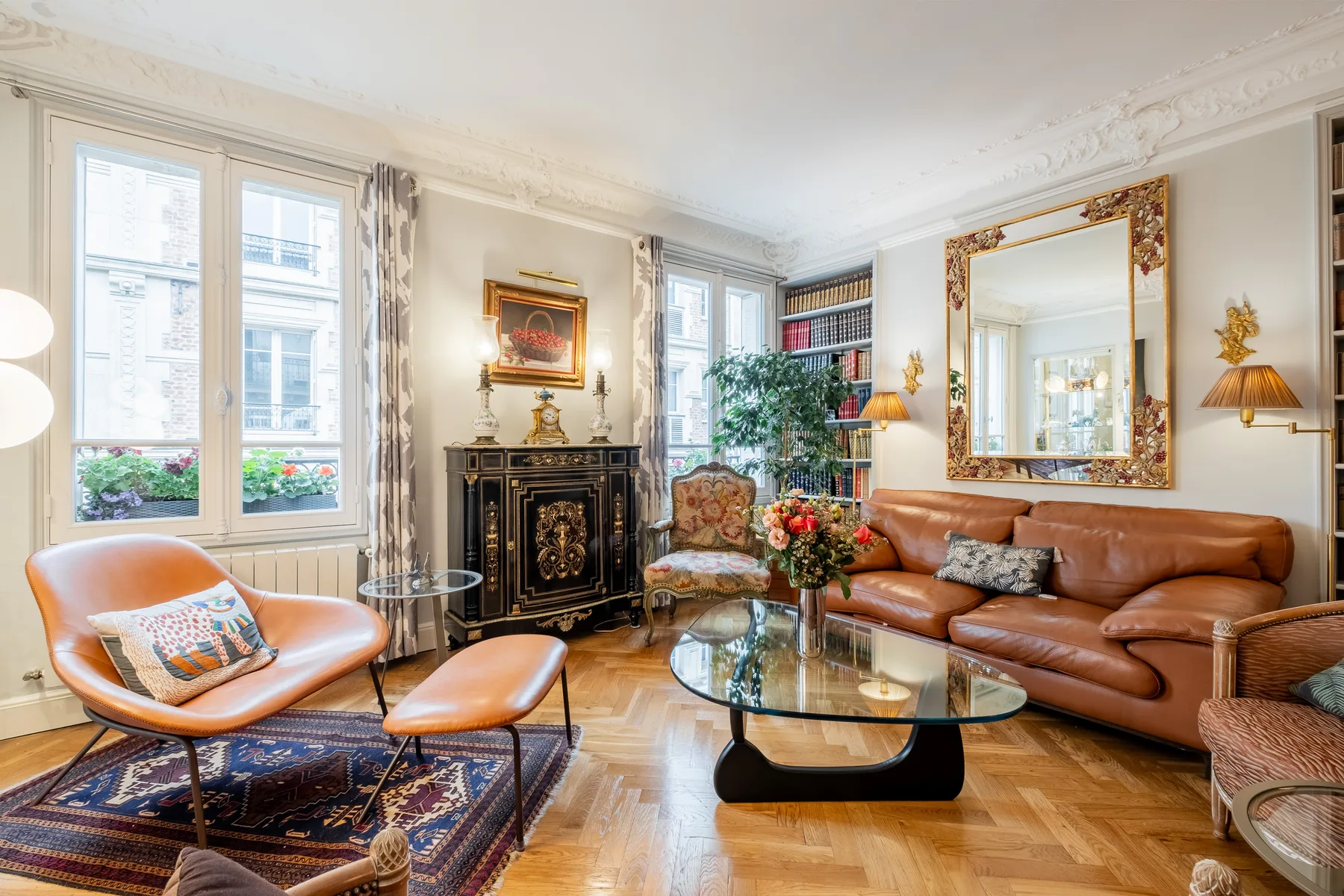 A bright living room with leather seating, a decorative fireplace, and tall windows.
