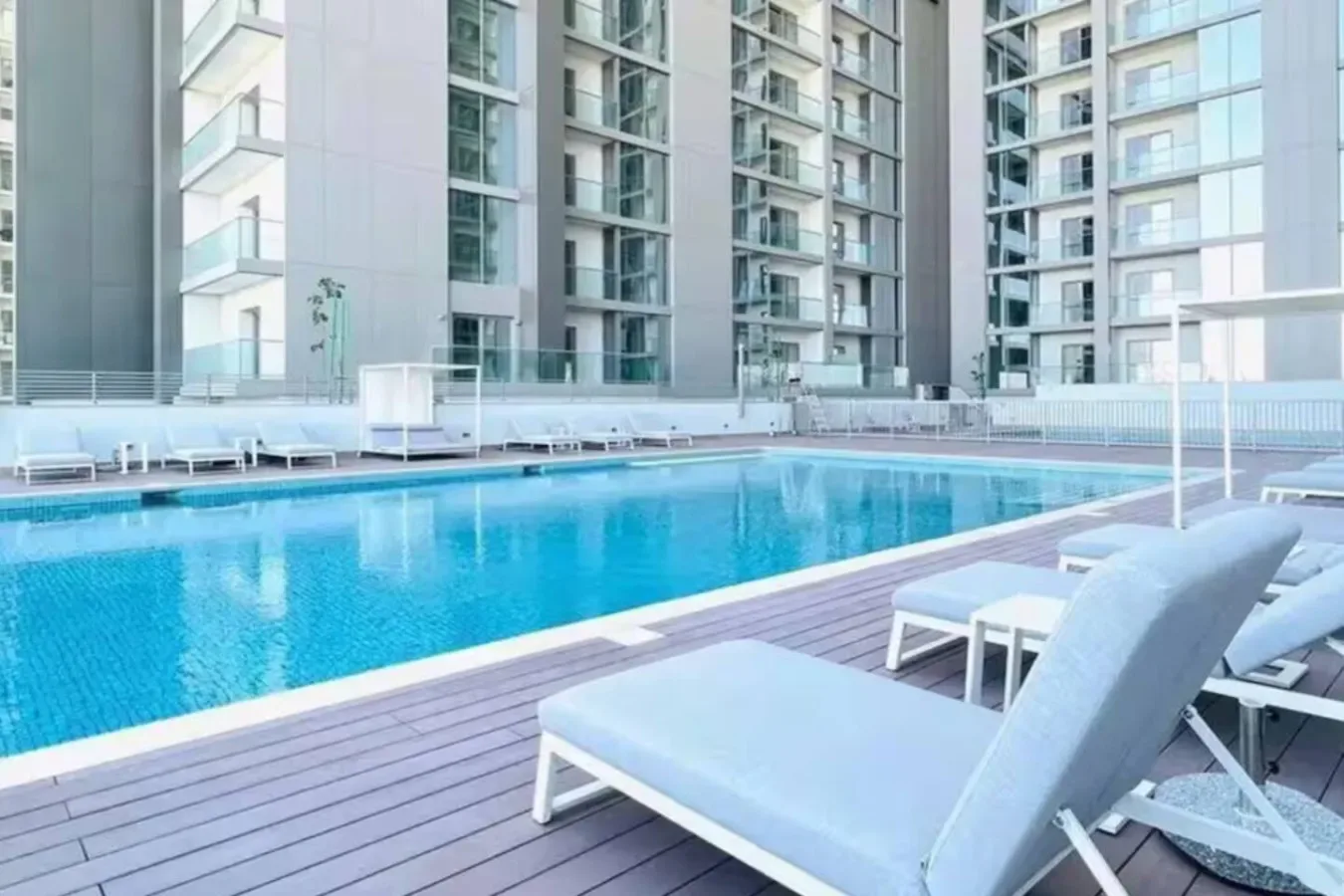 Una piscina con asientos junto a un edificio moderno de gran altura.