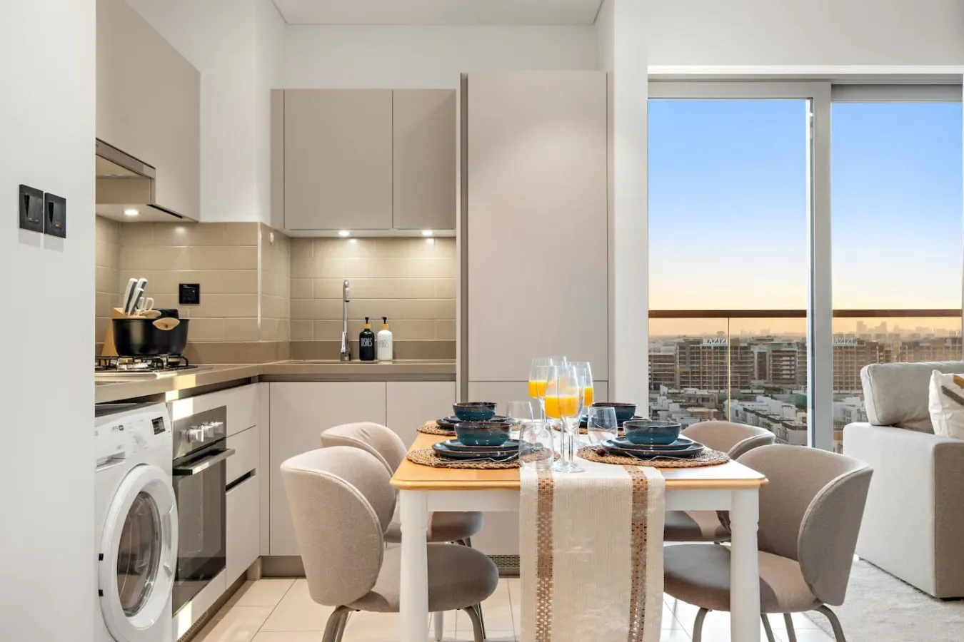 Comedor junto a una cocina compacta, con grandes ventanales con vistas a la ciudad.