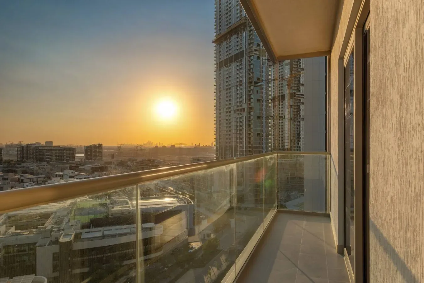 Un balcón da a edificios de la ciudad bajo la luz cálida del atardecer.