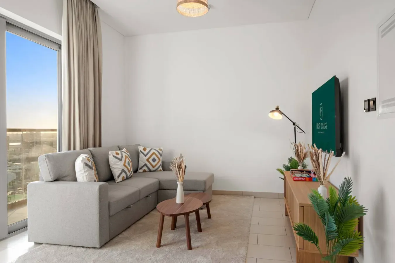 Una sala de estar con asientos grises, una mesa de centro y puertas corredizas de vidrio.