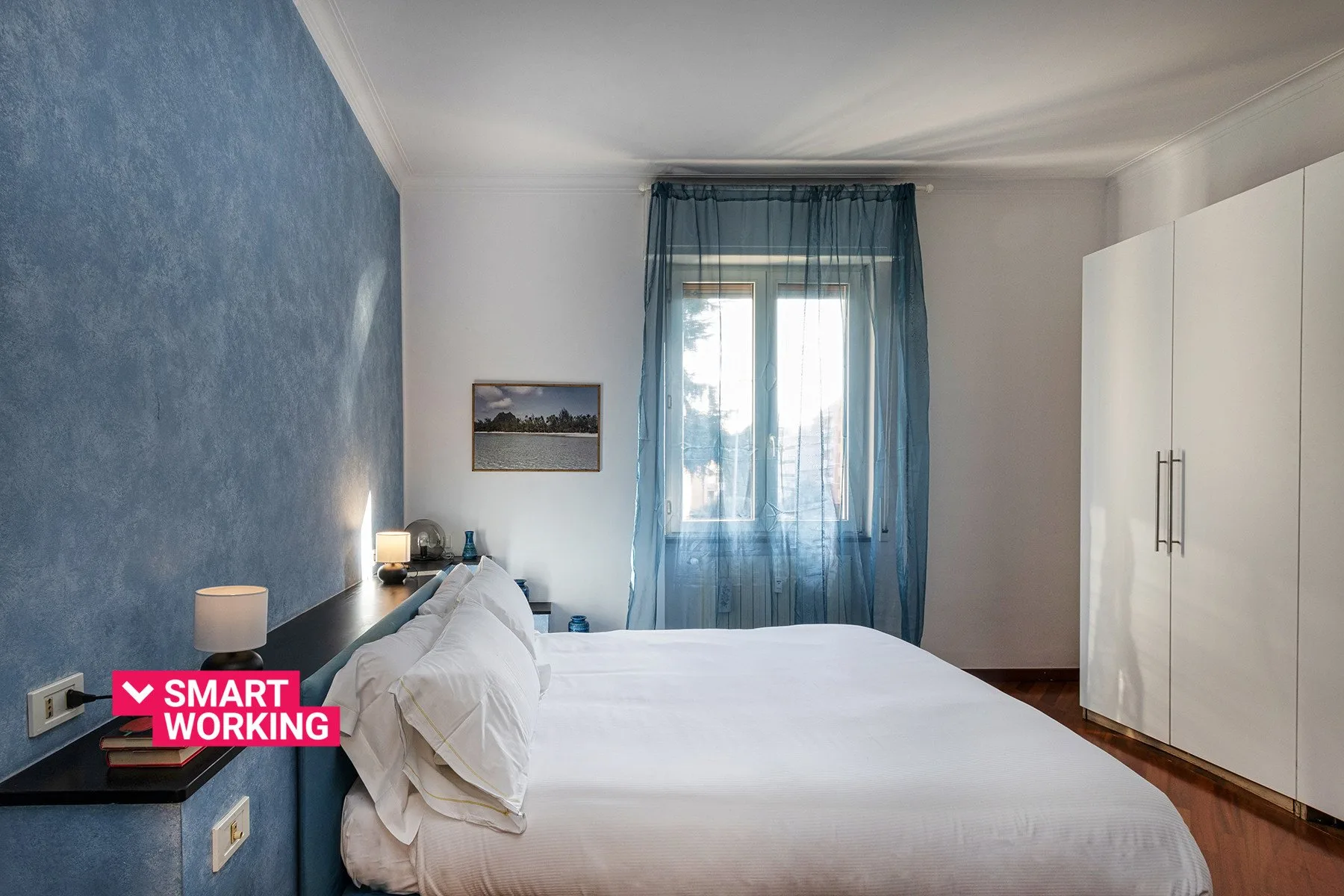 Un dormitorio con una cama hecha, cortinas azules y un armario blanco.