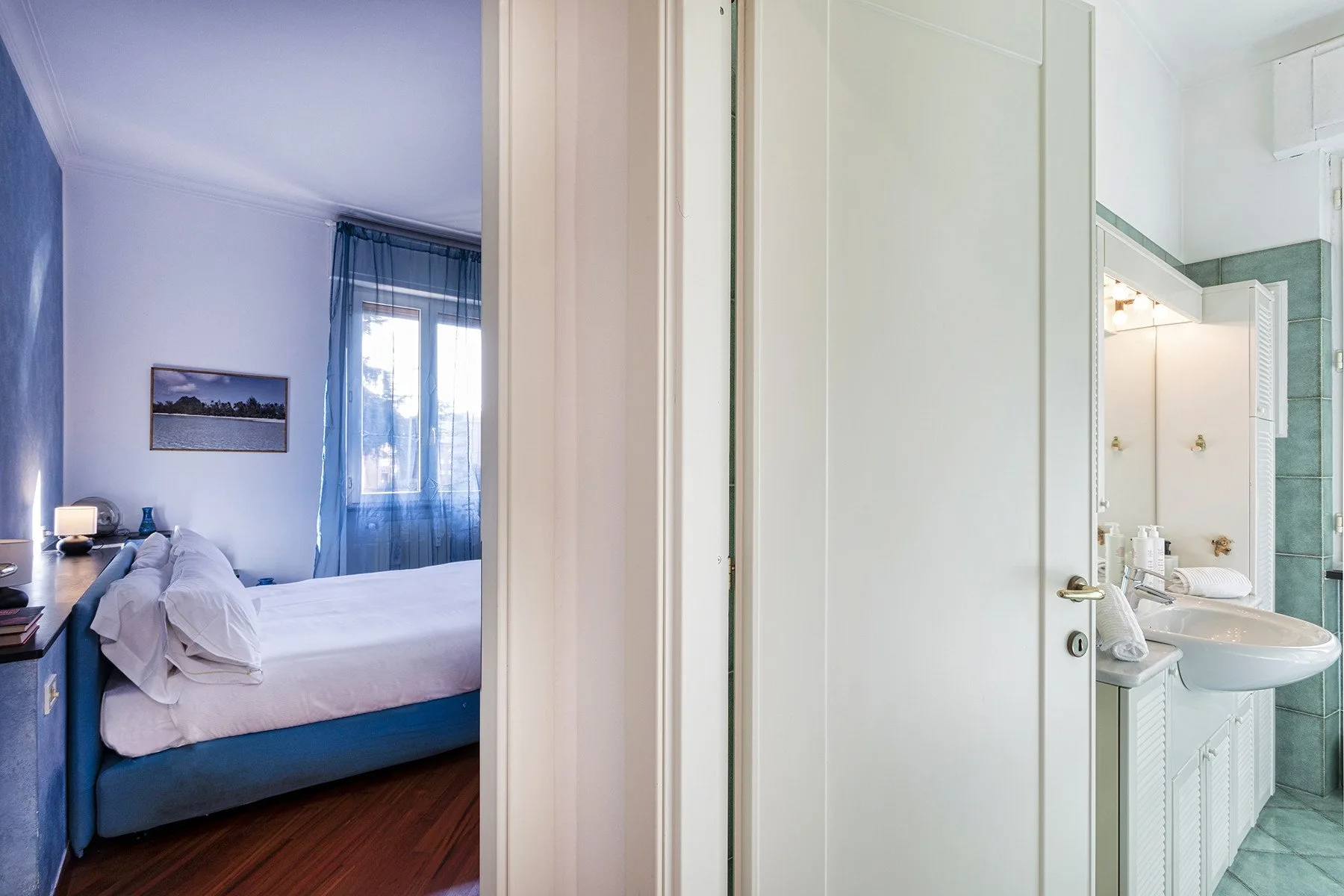 Se ve un dormitorio con una cama junto a un baño abierto con lavabo.