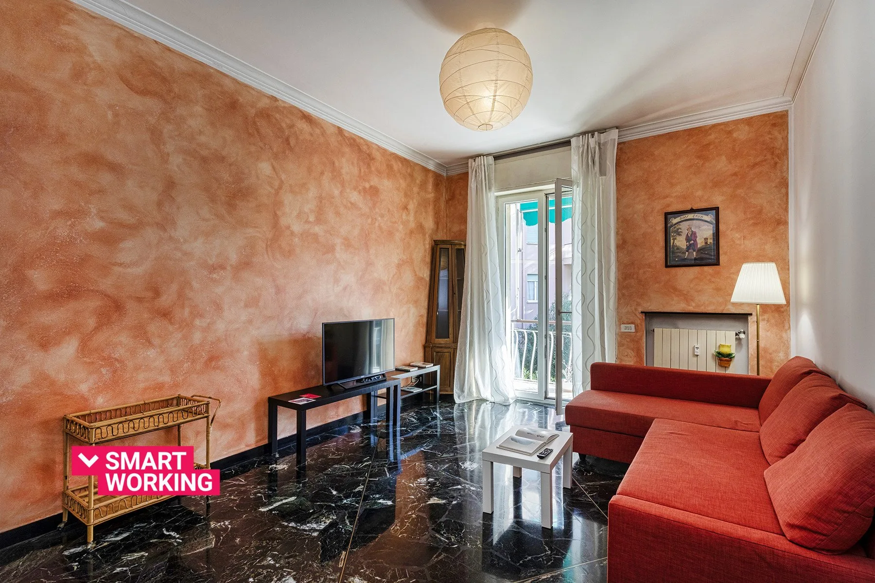 Una sala de estar con asientos rojos, un televisor y puertas altas de vidrio.