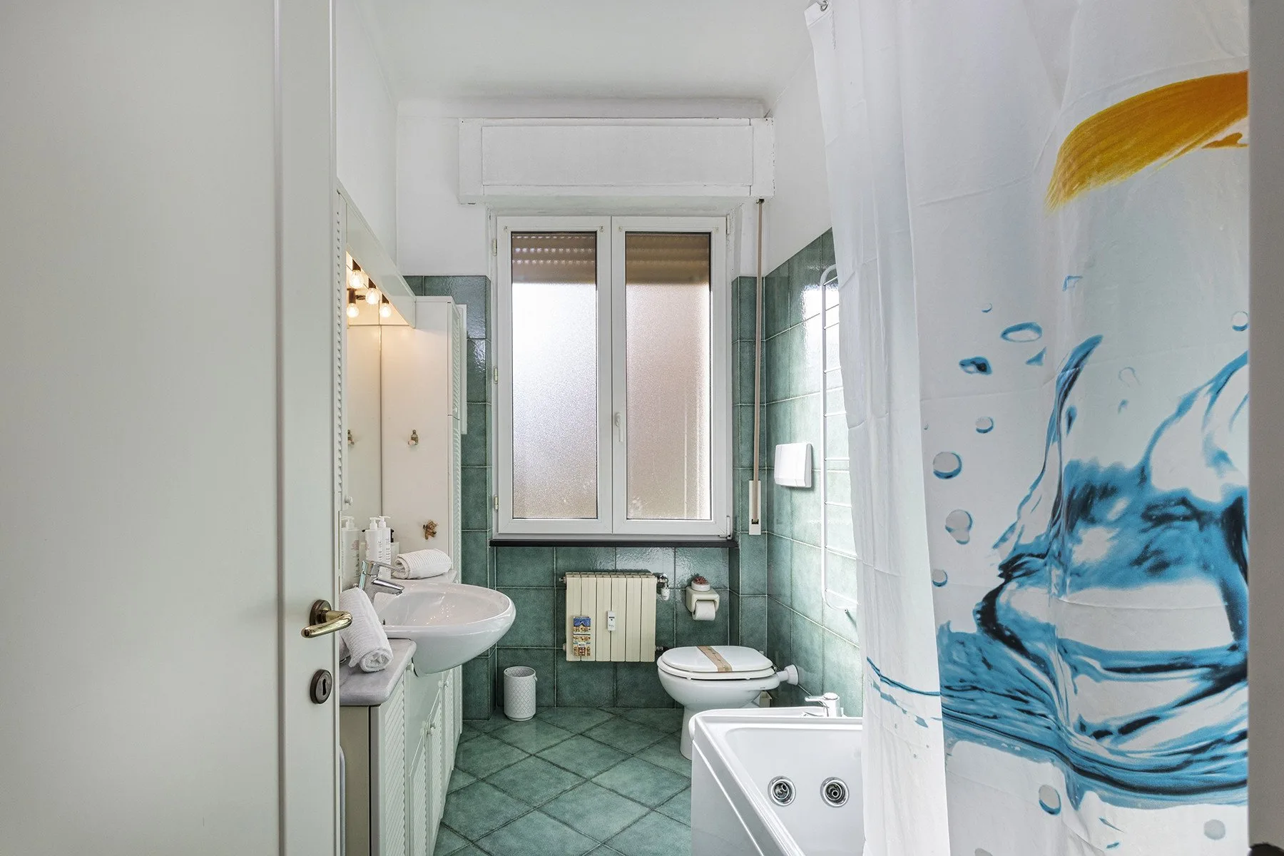 Un baño alicatado con lavabo, inodoro, bañera y ventana.
