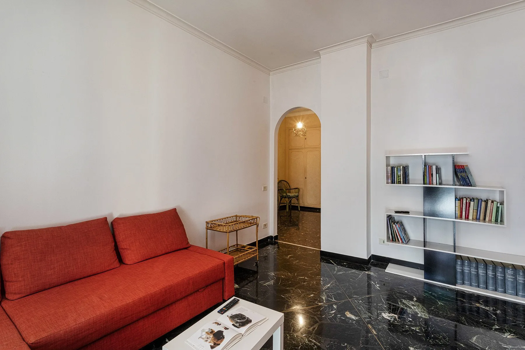 Una sala de estar con asientos rojos, una mesa baja y estanterías.