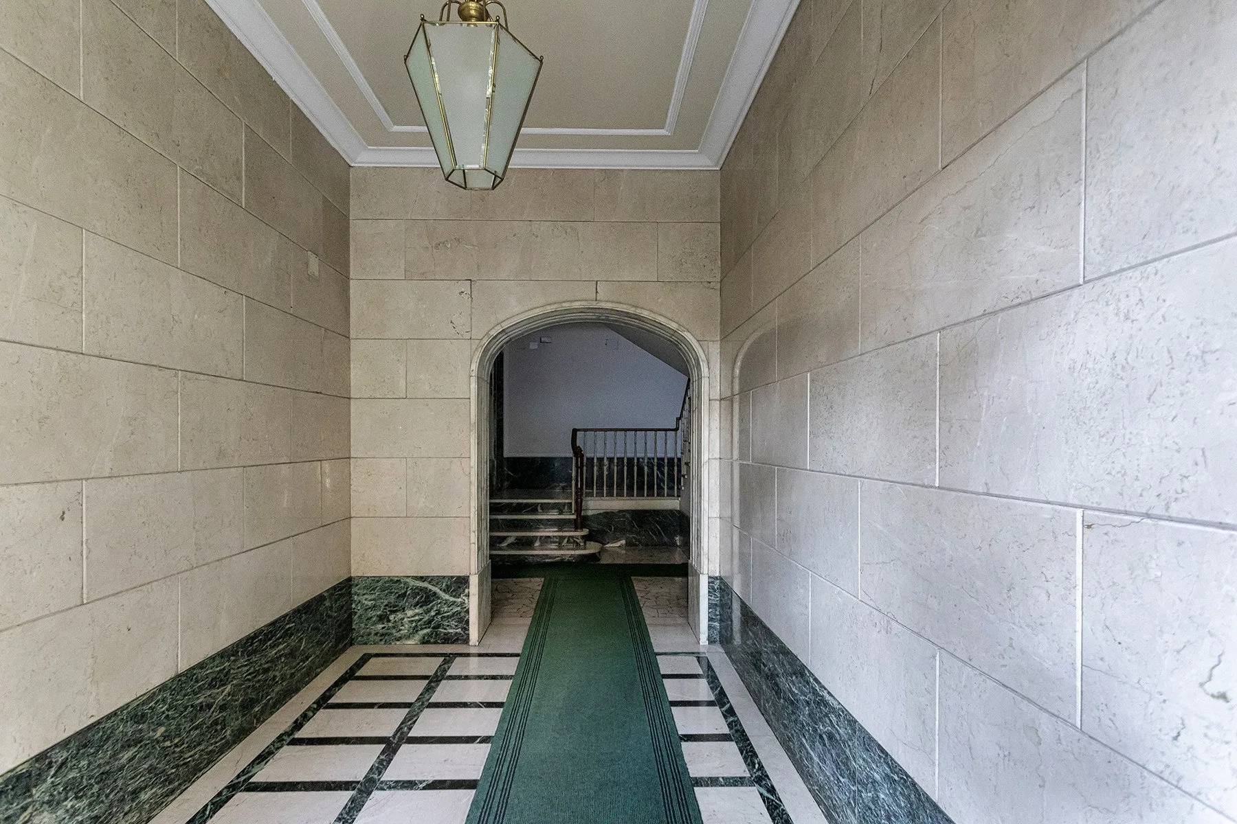 Un pasillo de azulejos conduce por un arco hacia una escalera.