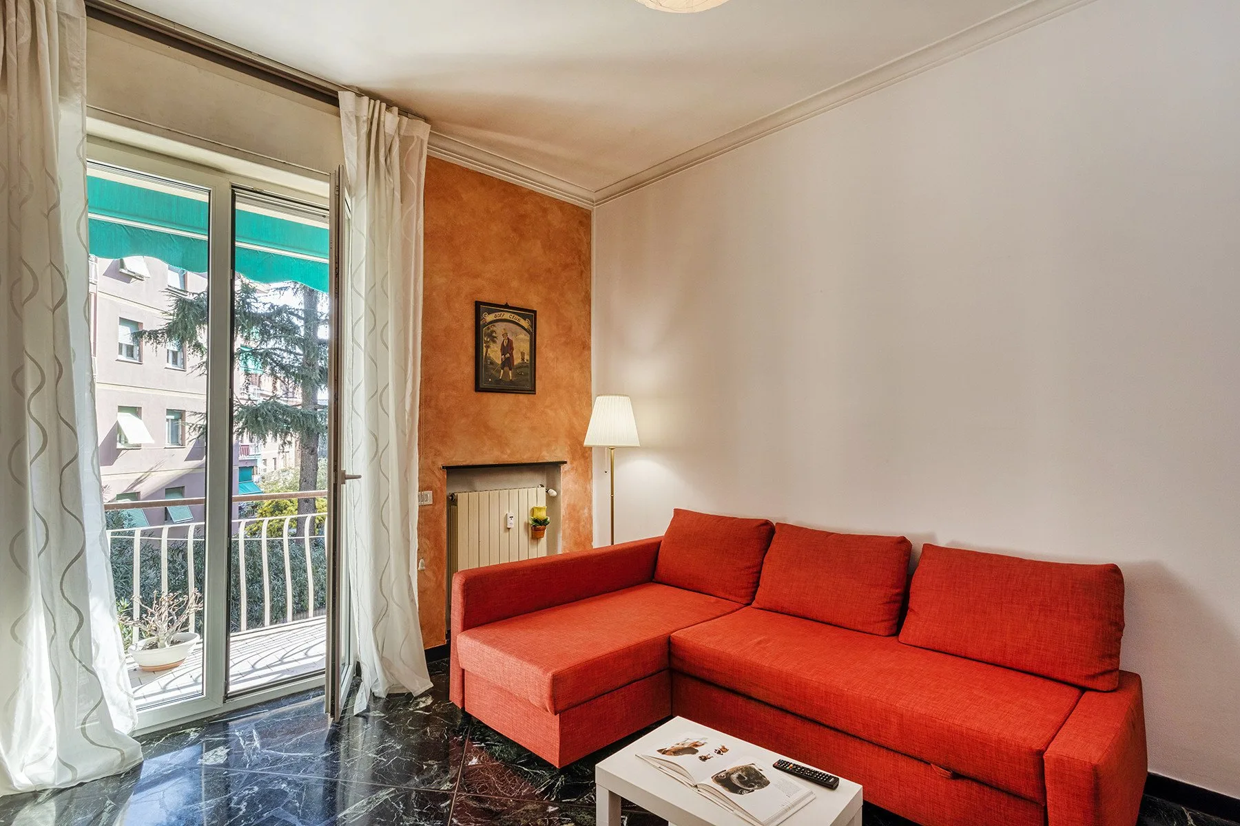 Una sala de estar con un sofá seccional rojo junto a una puerta de balcón.