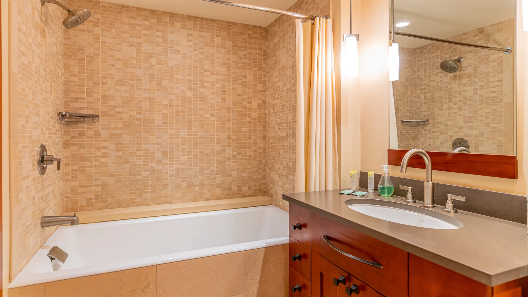 Un baño con bañera, paredes de azulejos y un mueble con lavabo.