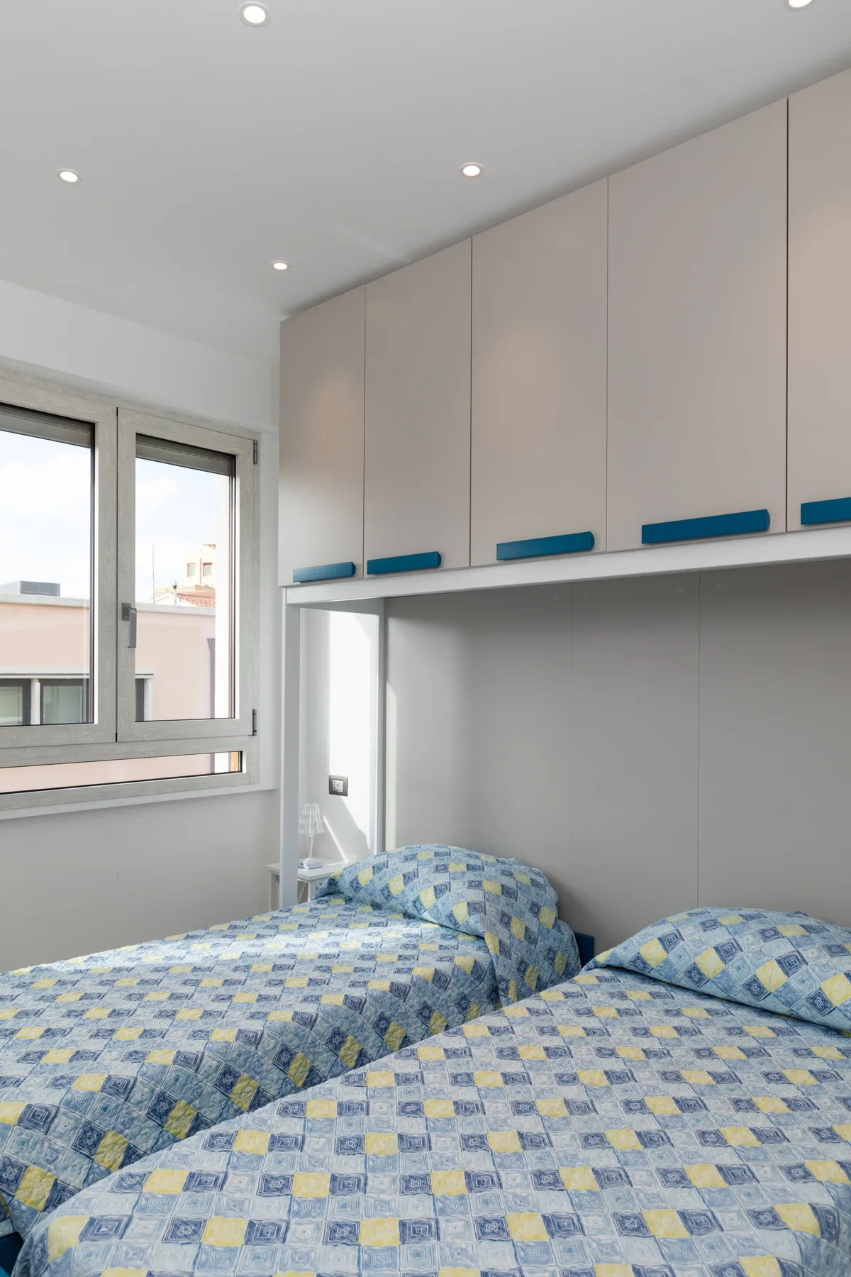 Un dormitorio con dos camas bajo una fila de armarios empotrados.