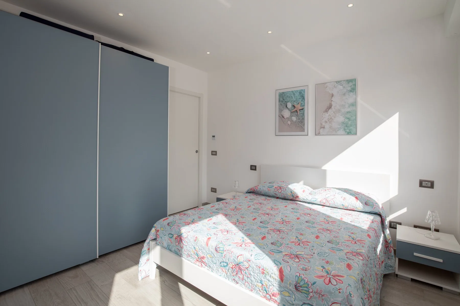 Un dormitorio luminoso con una cama cubierta con ropa de cama estampada y un armario grande.