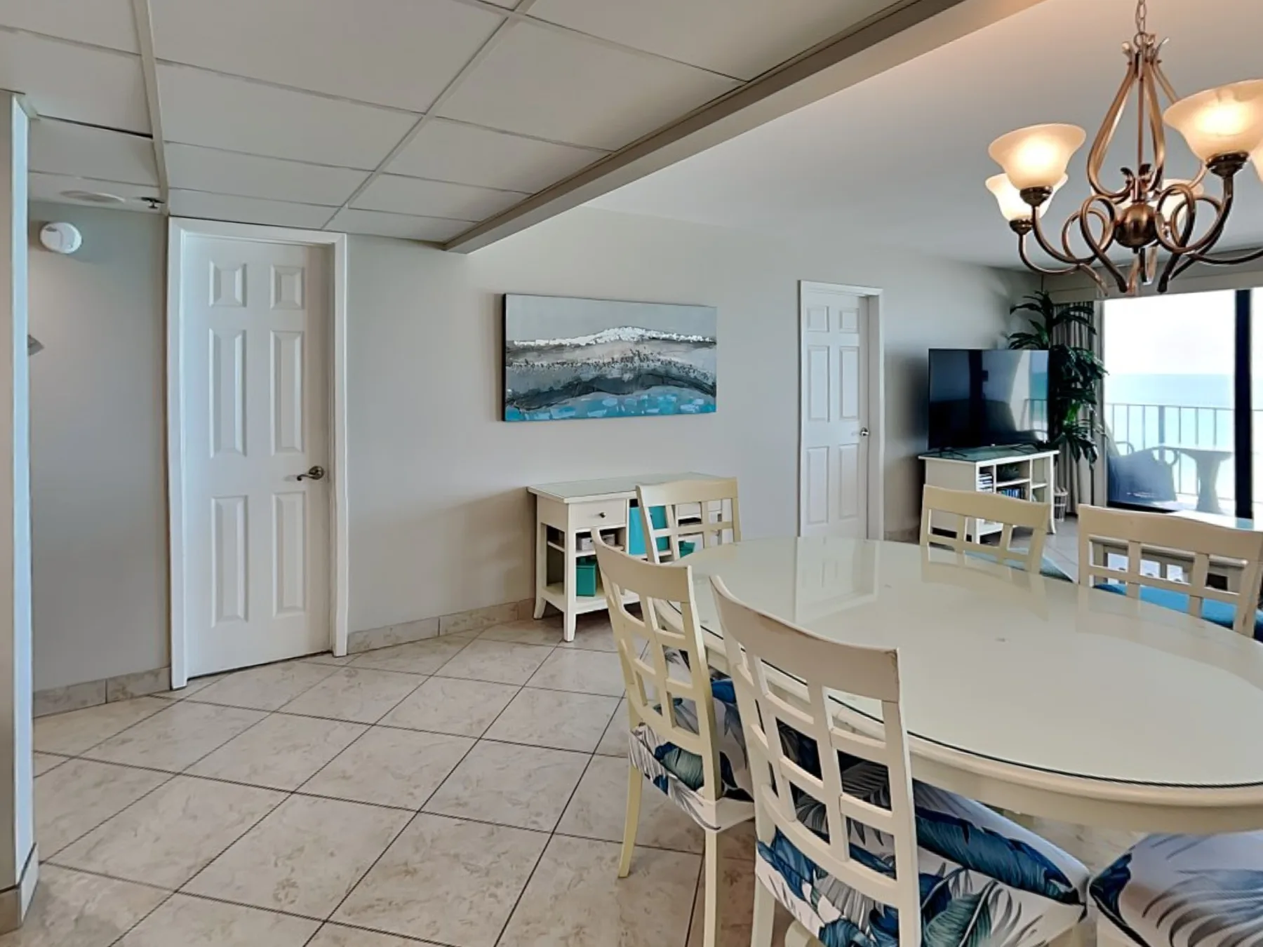 A dining area with a long table, chairs, and a television by the windows.