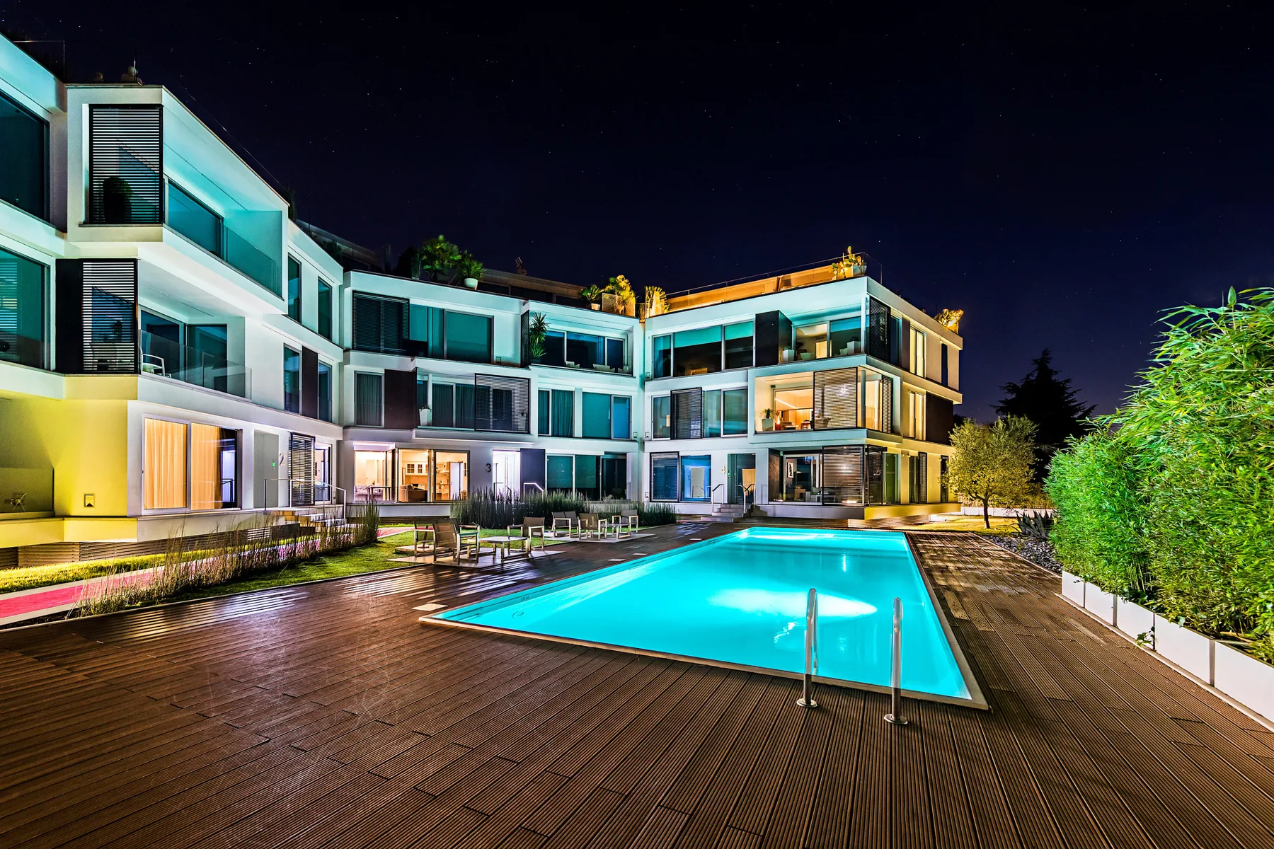 Un edificio moderno da a una piscina iluminada por la noche.