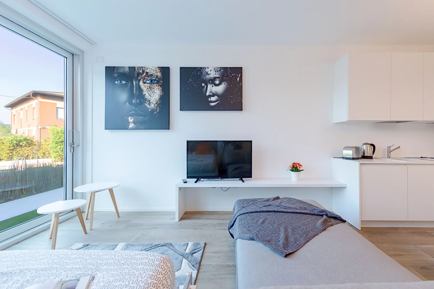 Una luminosa sala de estar con televisor, cuadros y una gran puerta de vidrio.