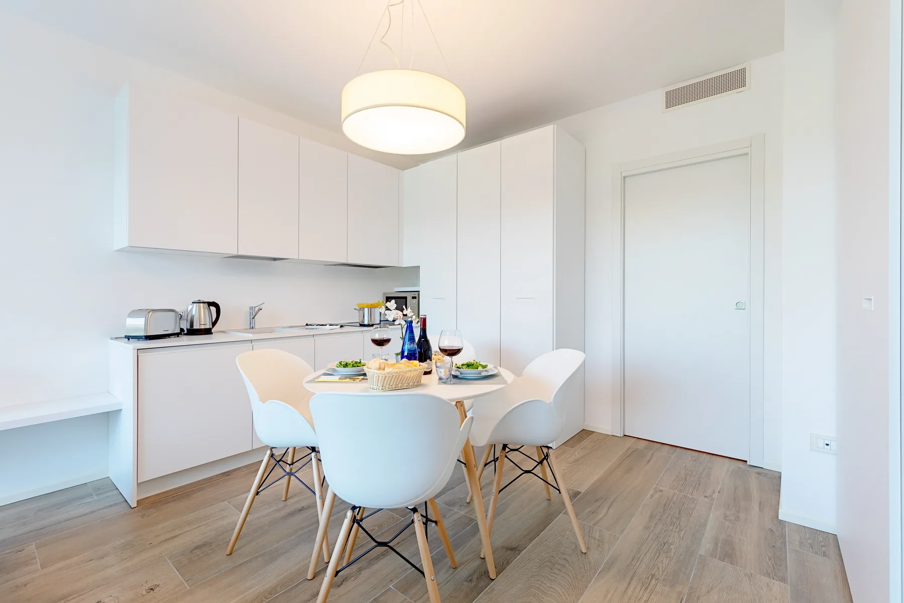 Un comedor luminoso con una mesa puesta junto a una cocina blanca.