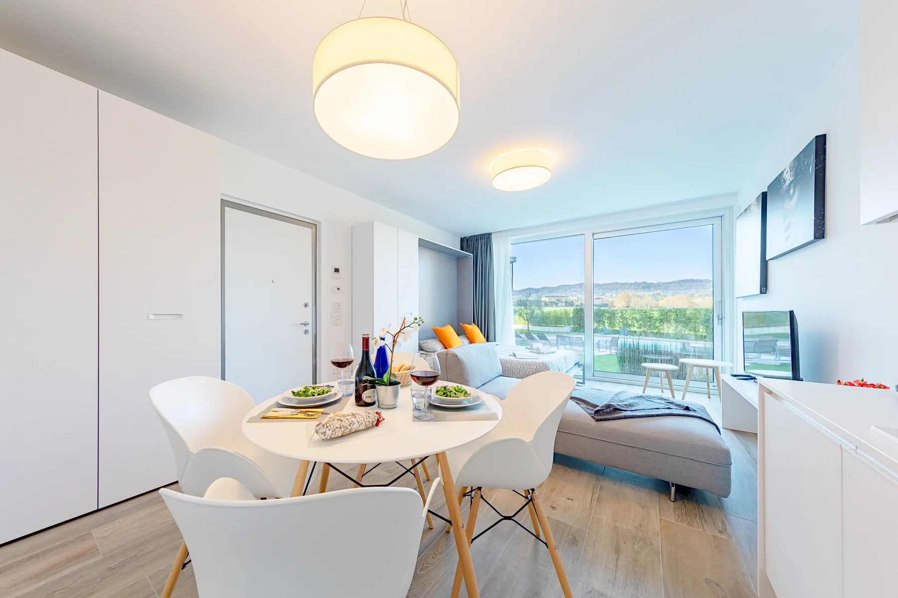 Una luminosa sala de estar y comedor con mesa, asientos y ventanales.