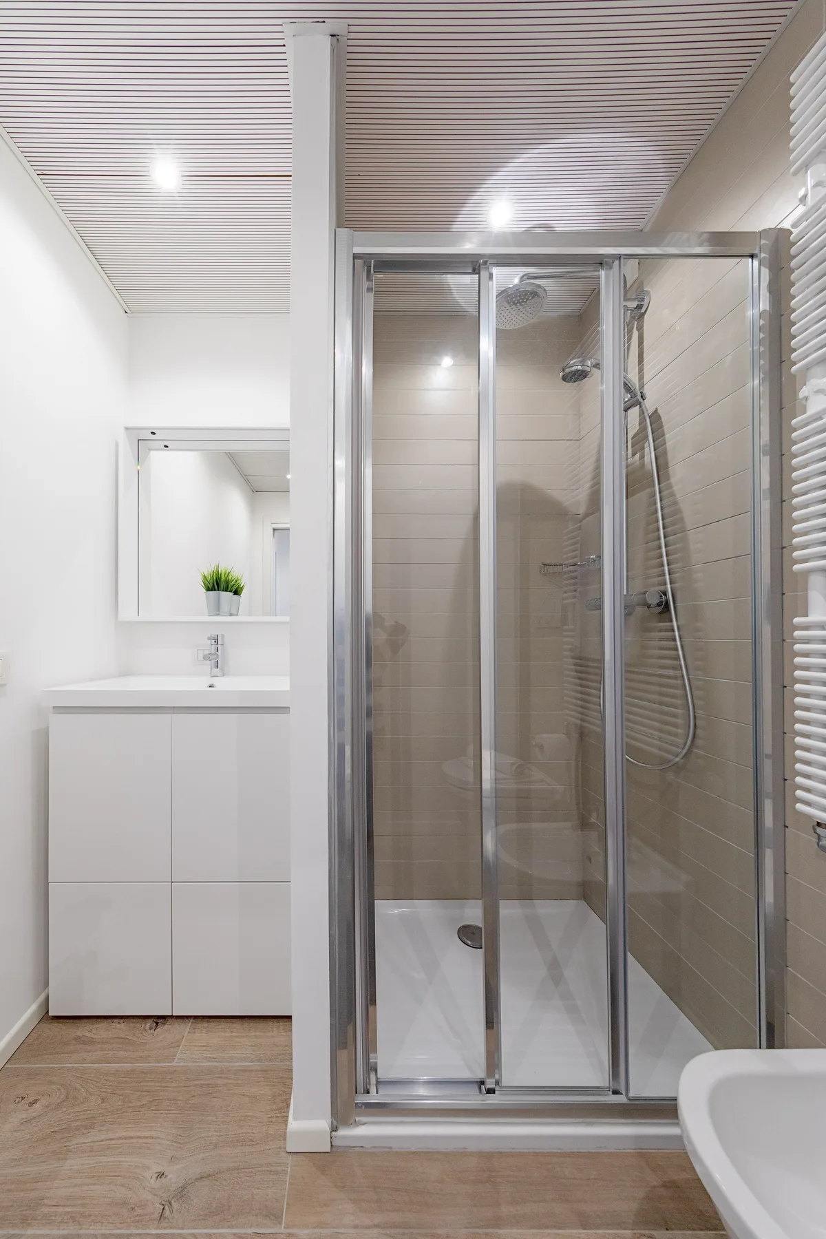Un baño luminoso con una ducha de vidrio y un tocador blanco.