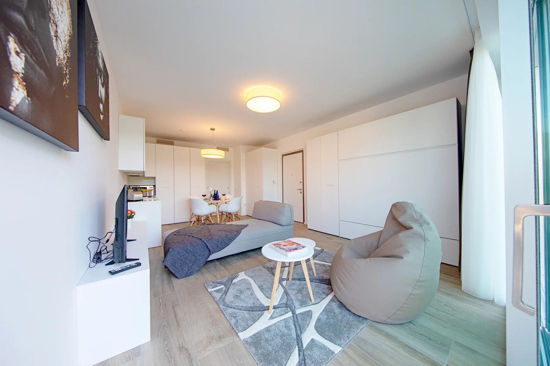 Una sala luminosa con sofá, asiento tipo puf y una mesa de centro pequeña.