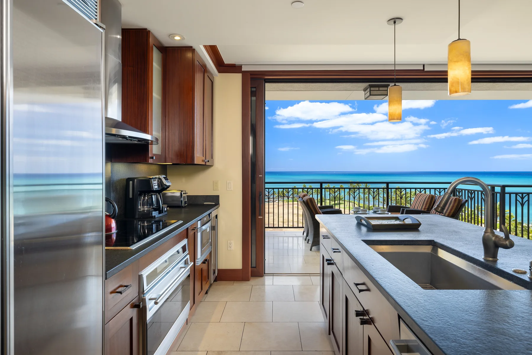 A modern kitchen opens onto a balcony overlooking the ocean.