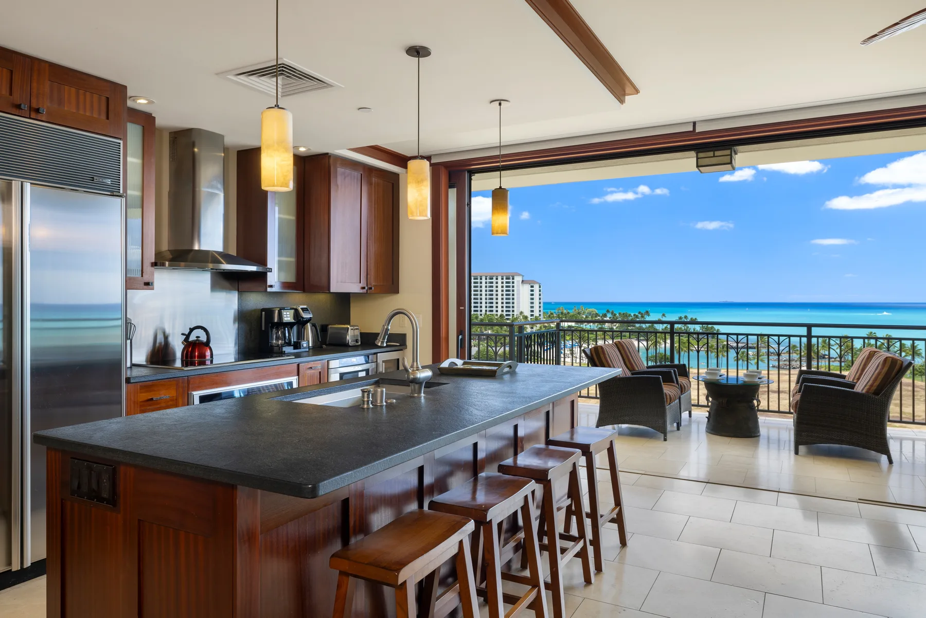Una cocina se abre a un balcón con asientos y vistas al mar.