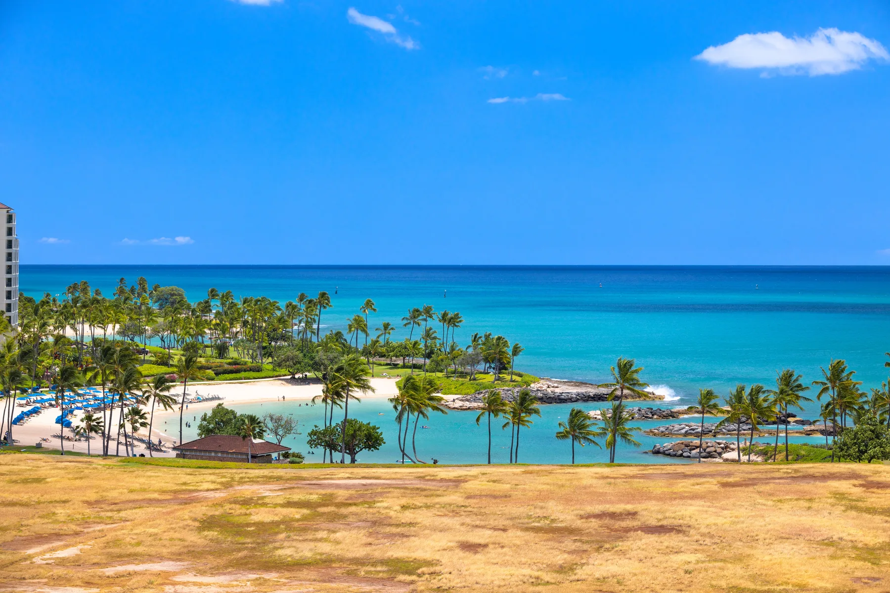 A tropical coastal landscape with palm trees, turquoise water, and a sandy beach.