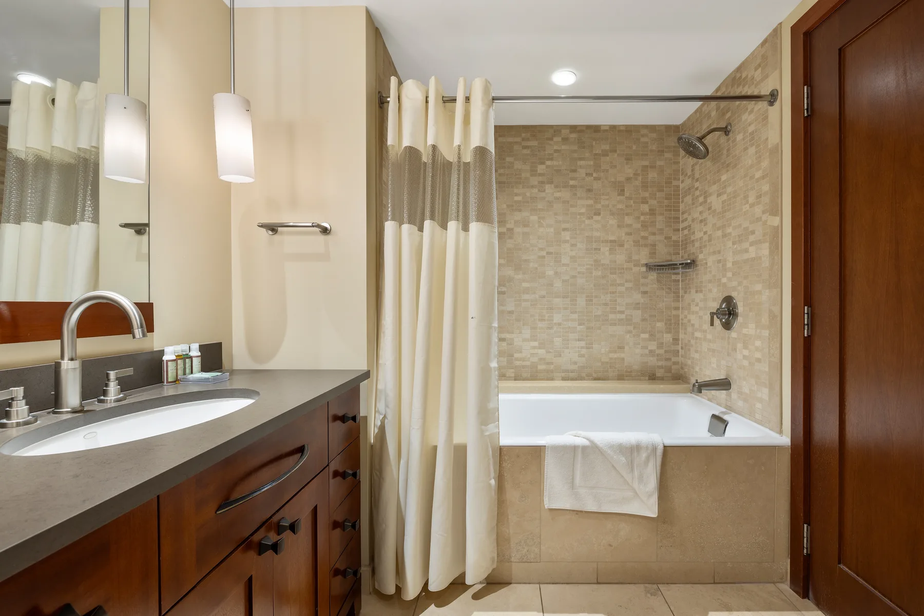A bathroom with a vanity beside a bathtub and shower curtain.