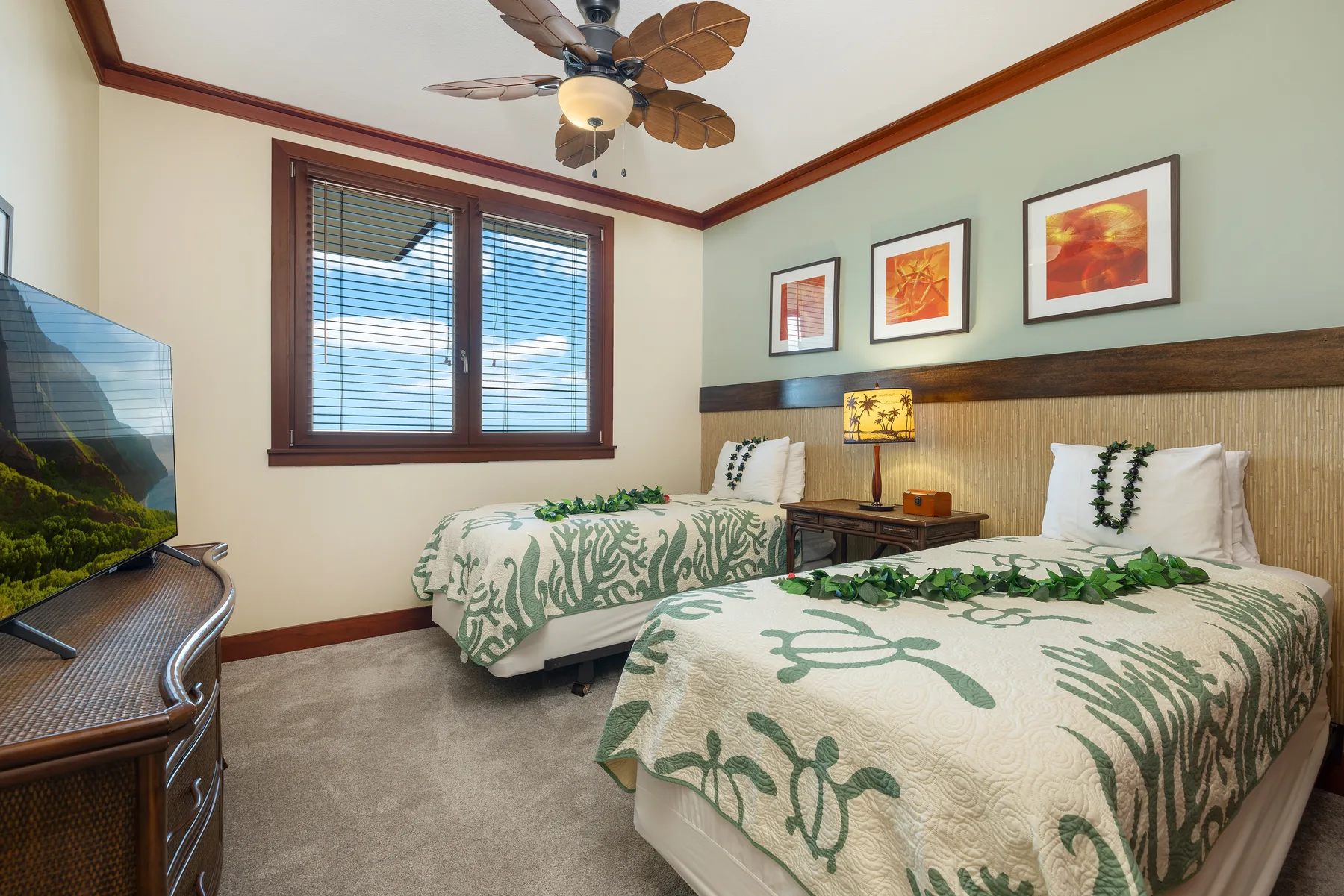 A bedroom with two beds dressed in green leaf-patterned bedding.